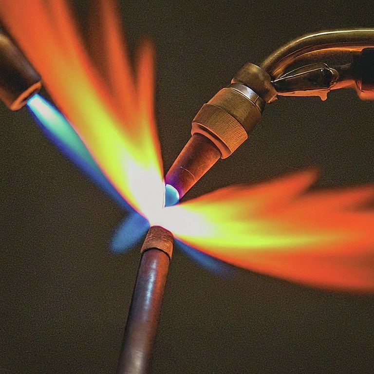 Brazing with a torch, creating a fiery flame.